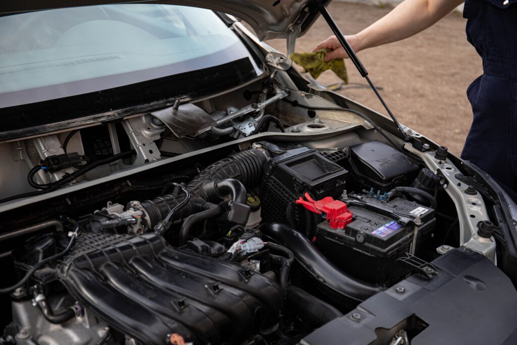 pexels photo 8478228 8478228 Mechanic inspecting car engine bay and battery during routine maintenance.